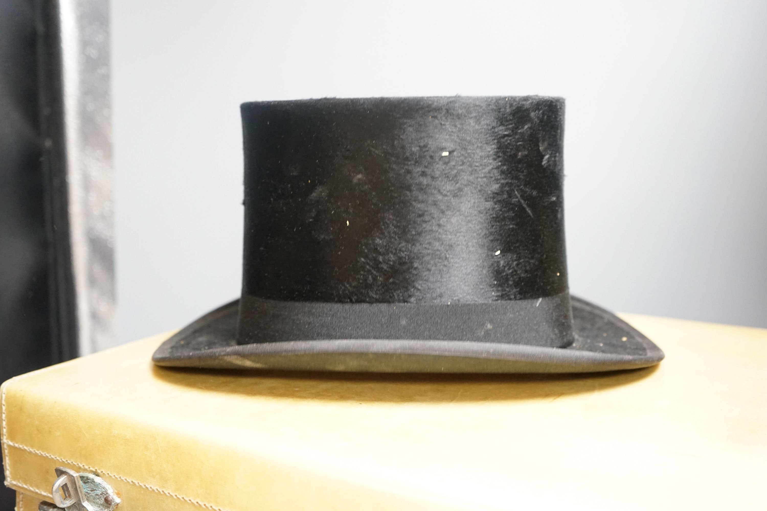 A top hat (boxed) and a cream vanity case